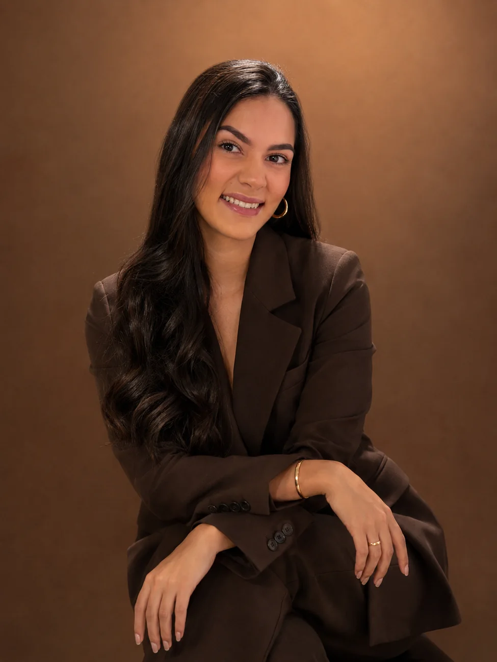 Sarah Yasmin sentada, de terno marrom